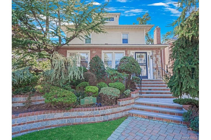 View of front of property with a chimney and brick siding