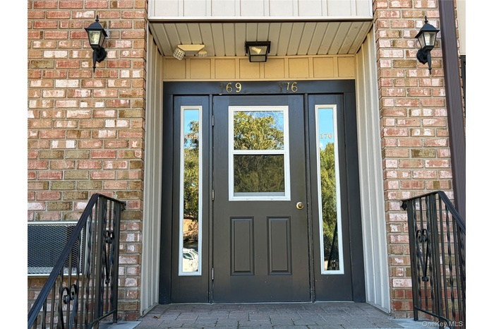 Doorway to property featuring brick siding, a patio, and board and batten siding