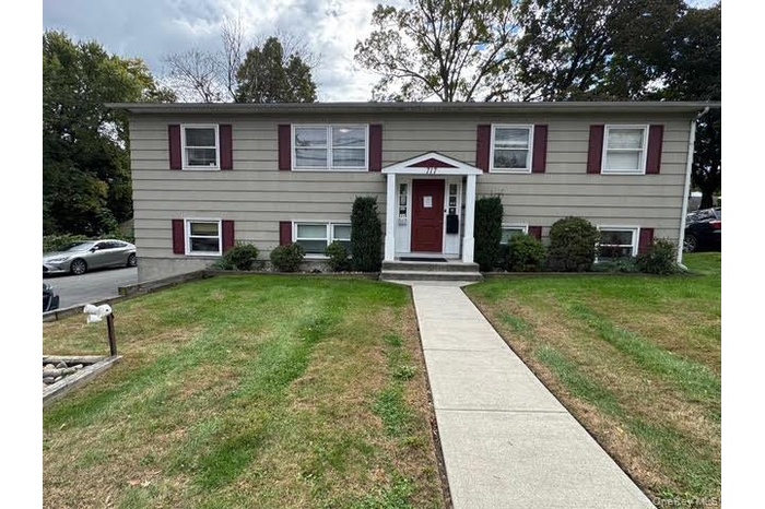 Raised ranch style structure with a front yard