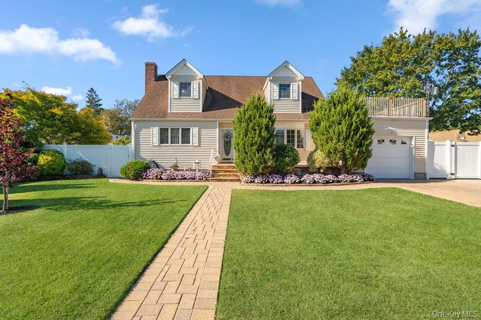Cape cod-style house featuring a chimney, a shingled roof, a gate, a garage, and driveway