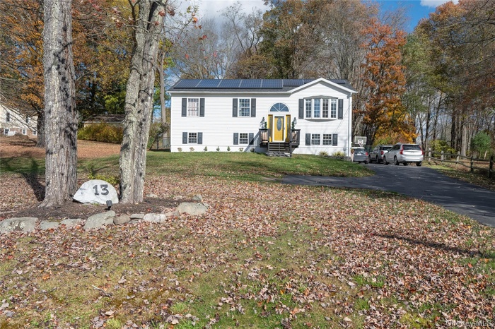 Split foyer home with roof mounted solar panels, a front lawn, and driveway
