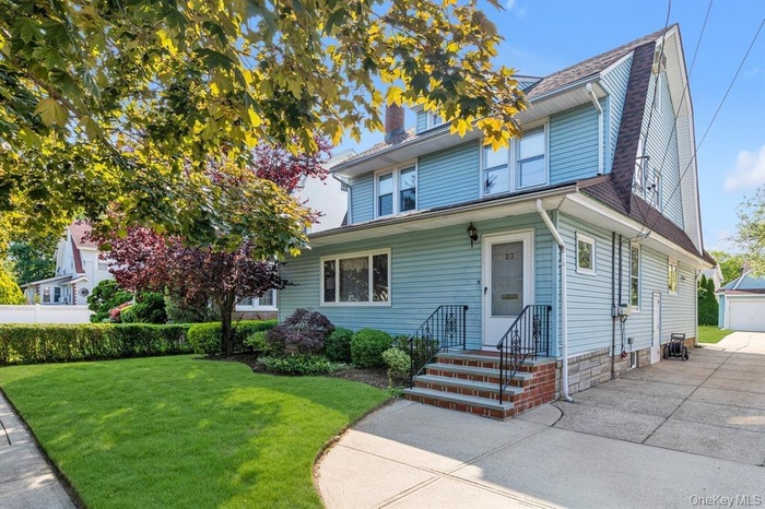 American foursquare style home with a front yard, a detached garage, and an outbuilding