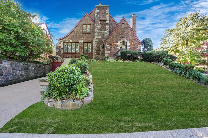 View of front of property with brick siding, a front lawn, and a chimney