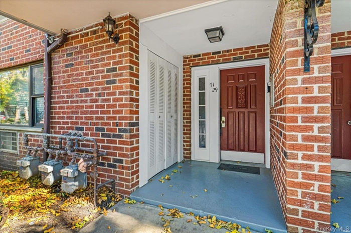 Entrance to property featuring brick siding and a porch