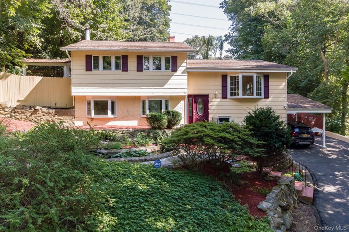 View of front facade with brick siding, a carport, and a chimney