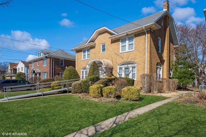 View of front of house featuring brick siding, a chimney, and a front yard