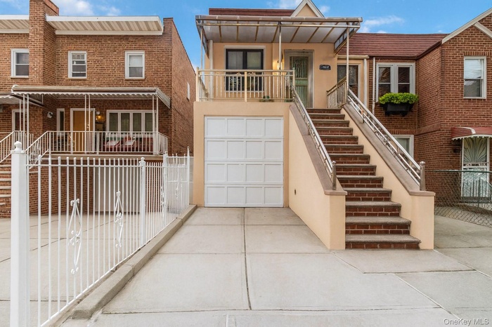 View of front facade with stairway, driveway, and a balcony