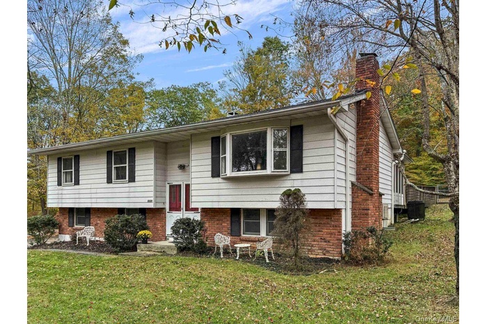 Split foyer home with a chimney, a front yard, and brick siding