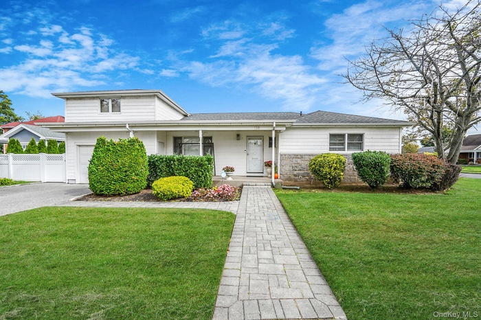 View of front of house featuring a porch, stone siding, asphalt driveway, and a shingled roof