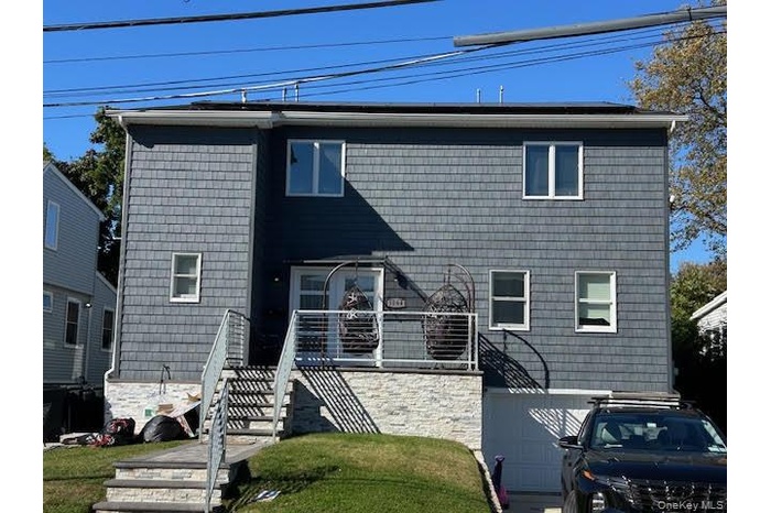 View of front facade featuring stairway, a garage, and a front yard