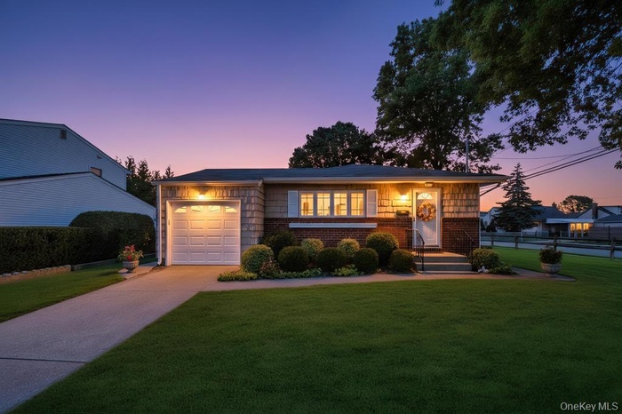 View of front of home featuring brick siding, concrete driveway, a yard, and a garage