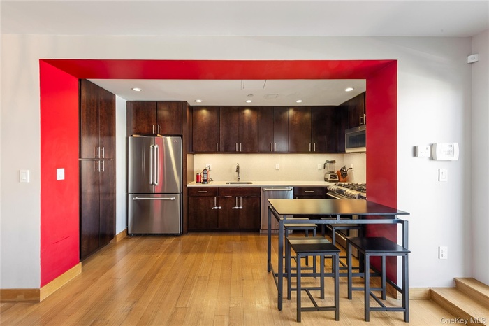 Kitchen featuring appliances with stainless steel finishes, dark brown cabinets, light wood-type flooring, and recessed lighting