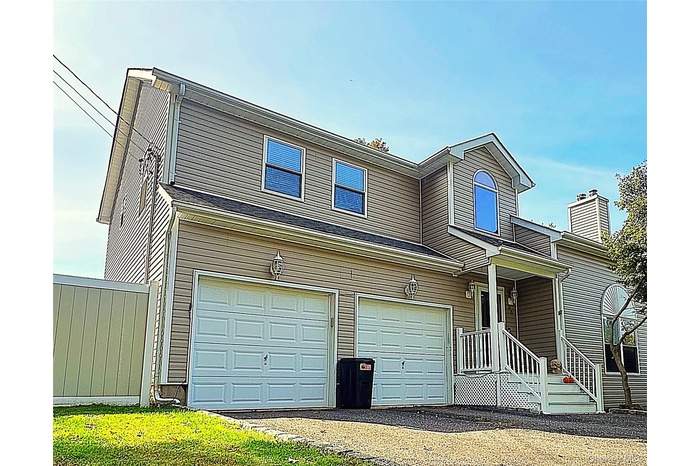 Traditional-style home with covered porch, an attached garage, and asphalt driveway