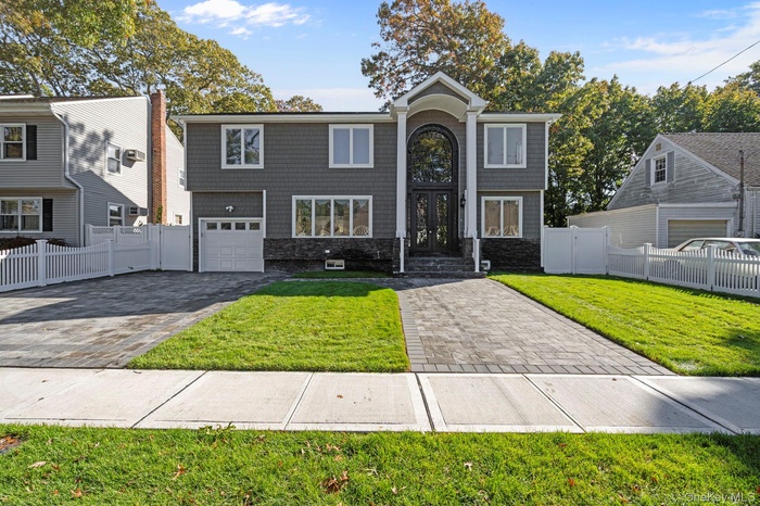 View of front of property with decorative driveway, a garage, and stone siding