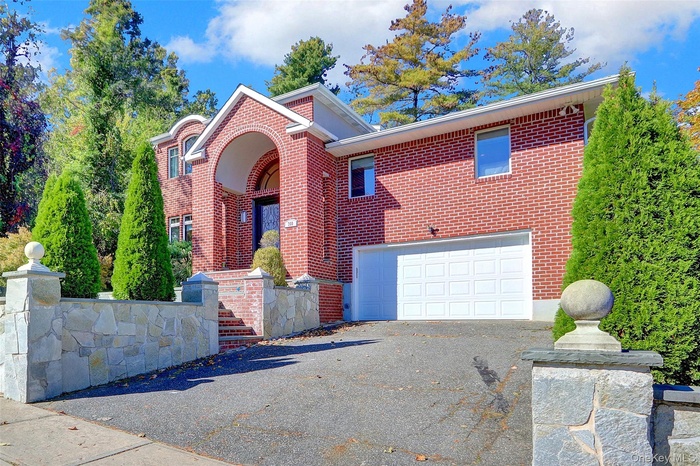 View of front facade with brick siding, driveway, and a garage