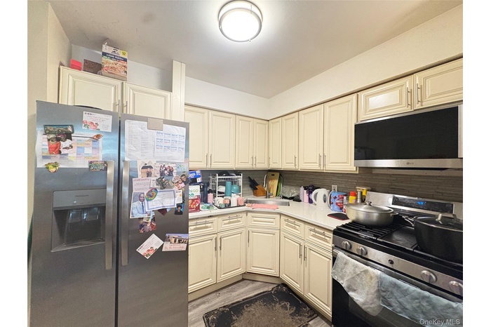 Kitchen featuring cream cabinetry, stainless steel appliances, backsplash, and light wood-style floors