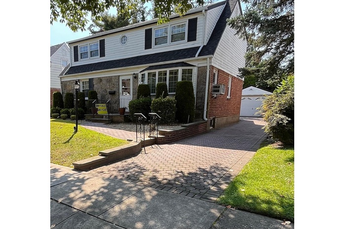 Traditional home featuring an outbuilding, a front lawn, brick siding, and a garage