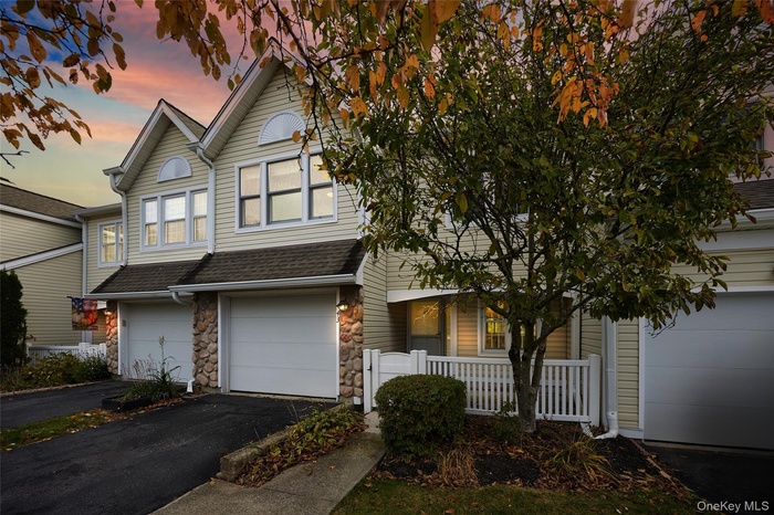 Traditional-style home featuring stone siding, roof with shingles, and asphalt driveway