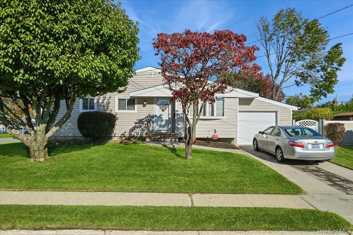 View of front facade featuring a front yard with paver pathway and steps, driveway, and a garage