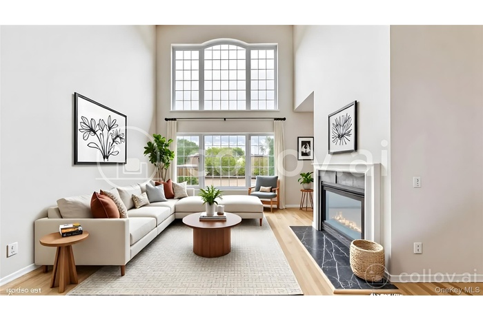 staged Living area featuring a towering ceiling, light wood-style floors, and a high end fireplace