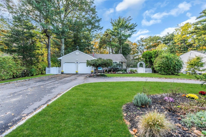 Ranch-style house with view of wooded area, asphalt driveway, and an attached garage