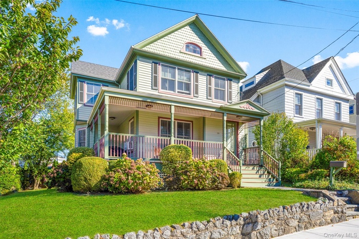 Victorian home with a porch and raised front lawn and retaining wall