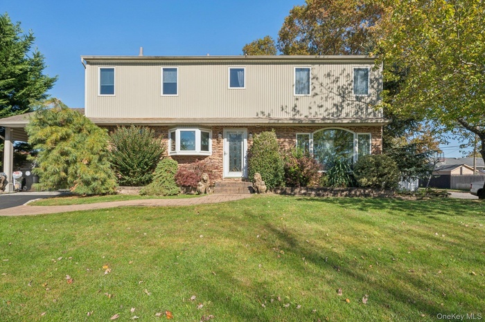Colonial house featuring a front lawn and brick siding