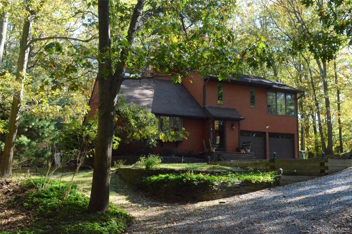 View of front of property featuring a garage and gravel driveway