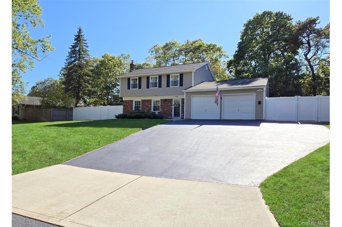 Colonial house with concrete driveway, brick siding, a chimney, and a garage