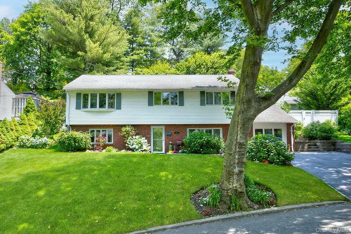Bi-level home featuring a front yard, brick siding, and a chimney