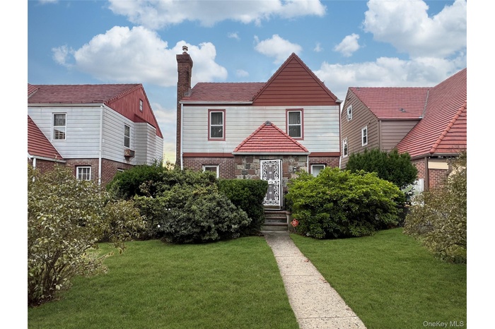 View of front facade featuring a front yard, brick siding, and a chimney