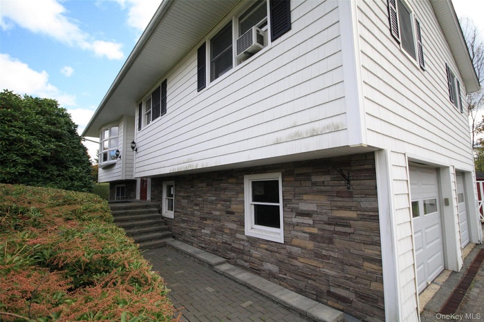 View of home's exterior with an attached garage and stone siding