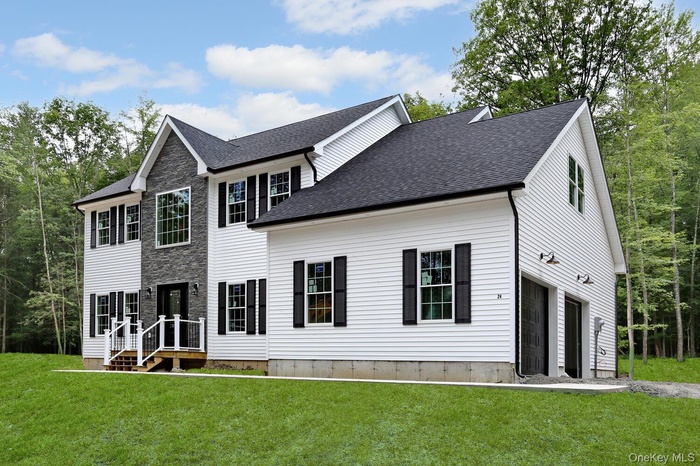 Rear view of property with a yard, a shingled roof, and stone siding