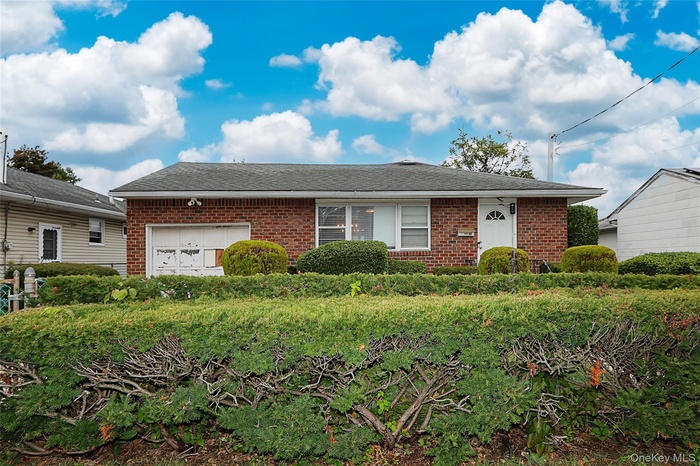 Single story home with brick siding, an attached garage, and a shingled roof