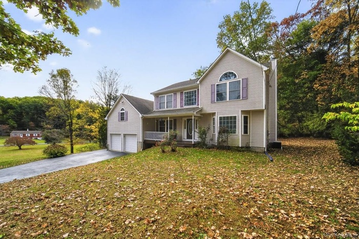 View of front of house featuring a porch, a chimney, asphalt driveway, a front yard, and a garage