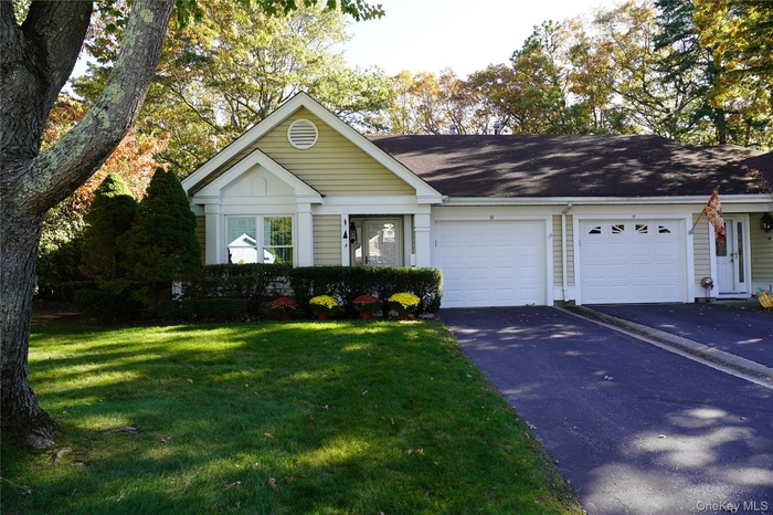 View of front of property featuring asphalt driveway, a front lawn, an attached garage, and roof with shingles