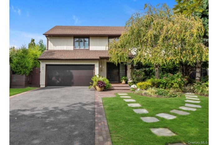 View of front of home with driveway, an attached garage, a front lawn, and roof with shingles