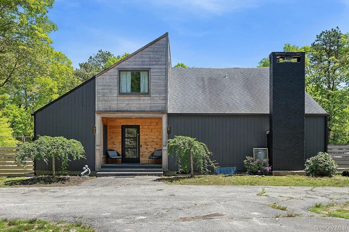 View of front of property with a chimney, a shingled roof, and covered porch