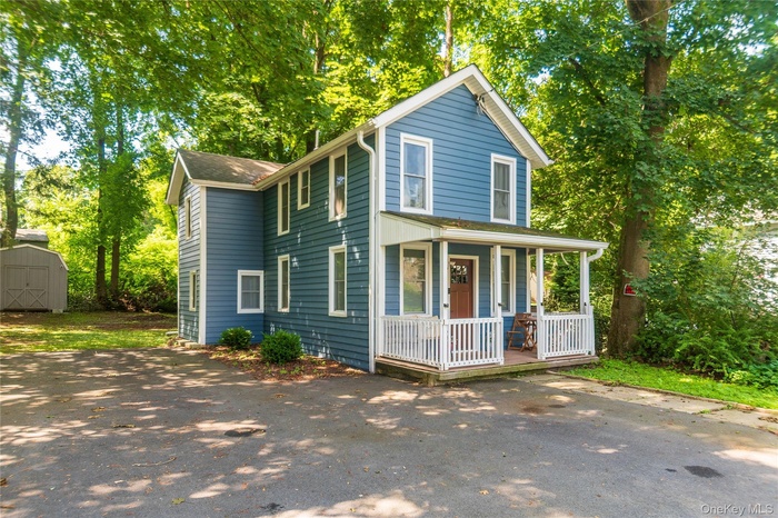 View of front of property featuring a porch and shed