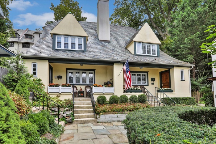 View of front of house featuring a high end roof, stucco siding, and a porch