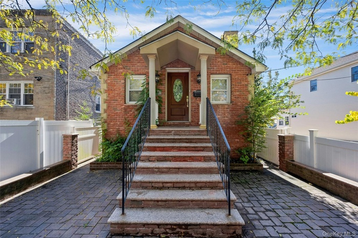 View of front facade featuring a chimney and brick siding
