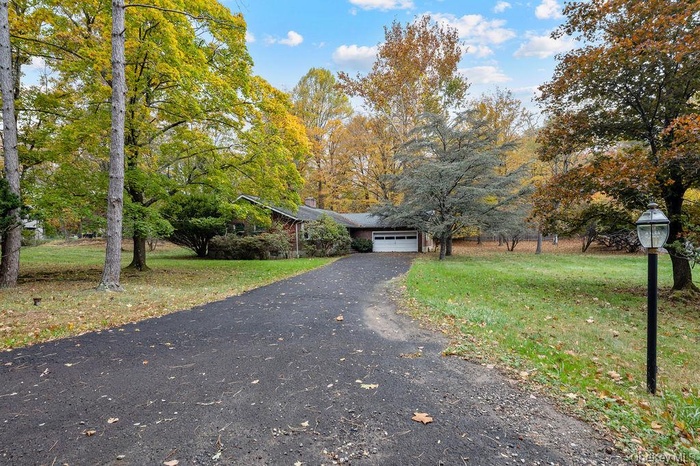 View of front of home featuring driveway, a front yard, a chimney, and an attached garage