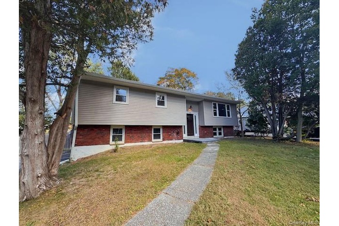 Raised ranch with a front yard and brick siding