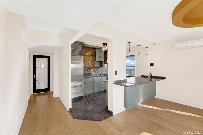 Kitchen with pendant lighting, decorative backsplash, dark wood-style floors, stainless steel built in fridge, and a wall mounted air conditioner