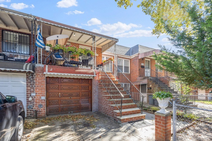 View of front of house featuring a balcony, brick siding, and a garage