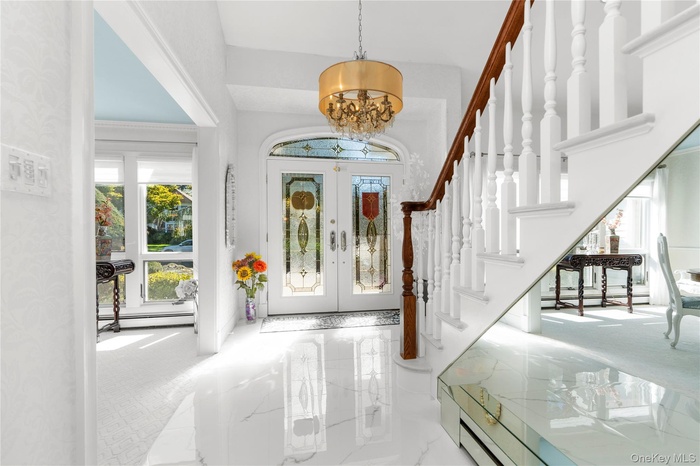 Foyer entrance featuring marble tiled flooring, a chandelier, french doors, stairway, and baseboard heating