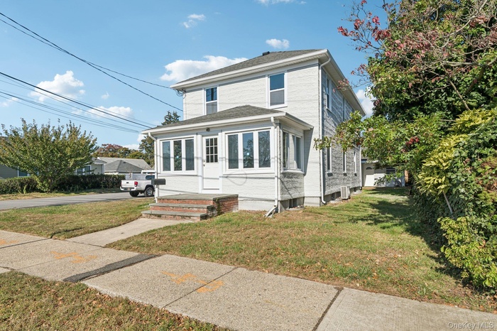 View of front facade featuring a front yard and a sunroom