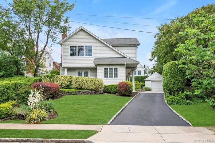 View of front of house featuring an outdoor structure, a garage, a front yard, a chimney, and roof with shingles