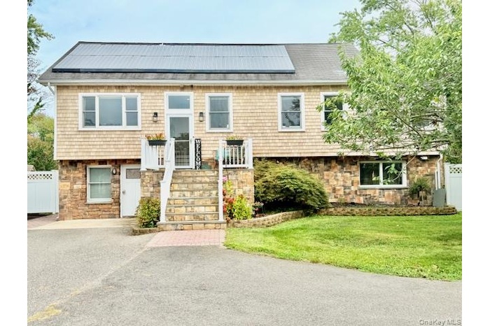 View of front of home featuring stone siding and roof mounted solar panels