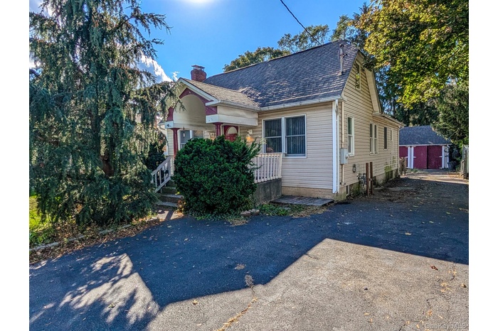 View of front of house with a chimney, a shingled roof, and asphalt driveway